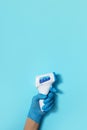 Hand in medical glove with digital infrared non contact thermometer gun for measuring temperature on blue background for Royalty Free Stock Photo