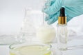 hand in medical glove holding glass vial with fermented product developed for cosmetic use. fermented beauty ingredients