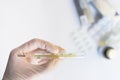 Hand in medical glove holding a thermometer with pills and medic