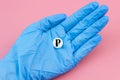 A hand in a medical glove holds a pill with a ruble sign on a pink background. Expensive medicine in Russia. Pharmaceutical