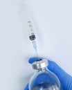 Hand in a medical glove holds a syringe, a bottle influenza