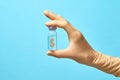 A hand in a medical glove holds a transparent bottle with a vaccine on a blue background. The bottle has a dollar sign Royalty Free Stock Photo