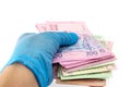 A hand in a medical glove holds Ukraine state money, hryvnia, on a white background isolated. Paid service concept