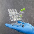 A hand in a medical glove holds a vaccine in a grocery cart