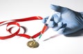 A hand in medical glove stabs a gold medal with popular red steroid in syringe on a white background