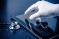 Hand in medical glove touching modern digital tablet pc near stethoscope Royalty Free Stock Photo