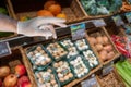 A hand in medical glove is trying to take food over grocery shelve shop with fresh vegetables and fruits, details, closeup