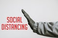 Hand in medical gloves gesturing stop with text social distancing