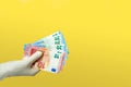 A hand in medical gloves holds euro notes isolated on a yellow background. quarantine cash donation concept