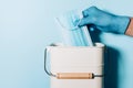 Hand in medical gloves throws medical mask into trash can on blue background. Quarantine over. Covid 19. Concept of coronavirus Royalty Free Stock Photo