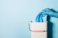 Hand in medical gloves throws medical mask into trash can on blue background. Quarantine over. Covid 19. Concept of coronavirus Royalty Free Stock Photo