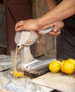 Hand of men is squeezing orange fruit using manual hand press juicer Royalty Free Stock Photo