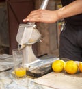 Hand of men is squeezing orange fruit using manual hand press juicer Royalty Free Stock Photo