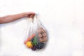 Hand with mesh textile bag with fruits