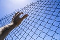 Hand on a metal fence. Border, prison, illegal migration concept.