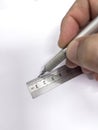 Hand with a metal mechanical pencil making a straight line with a metal millimetre ruler on a blank sheet of paper Royalty Free Stock Photo