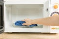 Hand with microfiber cleaning rag wiping inside of microwave oven, Royalty Free Stock Photo