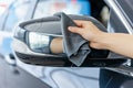 hand with a microfiber cloth buffing a cars side mirror