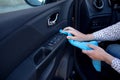 Hand with a microfibre cloth cleans the interior of the car