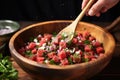 a hand mixing a bowl of watermelon salad with a wooden spoon Royalty Free Stock Photo