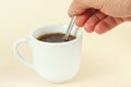 Hand mixing with a spoon of aromatic coffee in cup