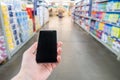 Hand with mobile phone on a background of a blurry shopping center.