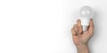 Hand with modern LED light bulb on a white table background with copy space, top view photo Royalty Free Stock Photo