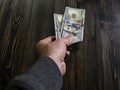 Hand with money on a wooden background. hand holding two 100 dollars banknote. US dollars in man hand Royalty Free Stock Photo