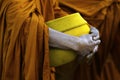 Hand of monk dressing orange robe, holding bowl during reception of alms Royalty Free Stock Photo