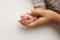 The hand of a mother and father close-up holds the fist of a newborn baby Royalty Free Stock Photo