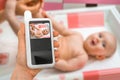 Mother is holding baby monitor camera for safety of her baby Royalty Free Stock Photo