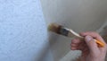 applying glue with a brush to the wall along the edge of the wallpaper