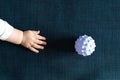 Hand of newborn baby boy with ball toy on dark blue background Royalty Free Stock Photo