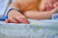 Hand newborn baby with a maternity hospital bracelet on his arm is sleeping in a crib. A newly born child in a clinic bed behind a Royalty Free Stock Photo