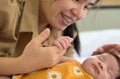 Newborn baby girl holding mother hand. Smiling mom and child on white bed Royalty Free Stock Photo