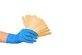 Hand in a nitrile blue glove holds a lot of wooden cosmetic spatulas on a white background