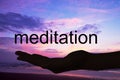 Hand offering the word meditation, sunset background