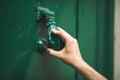 A hand on an Old door knocker of historical building clode up. Doorknob in a shape of woman hand, on a green door Royalty Free Stock Photo