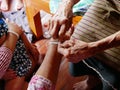 Hand of old woman waving a white string Sai Sin around her daughter`s hand - Thai traditional blessing from an elder one Royalty Free Stock Photo