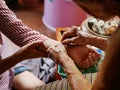 Hand of old woman waving a white string Sai Sin around her granddaughter hands - Thai traditional blessing from an elder one