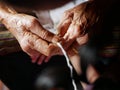 Hands of old woman tying white string  Sai Sin  around her granddaughter hands - Thai traditional blessing from an elder one Royalty Free Stock Photo