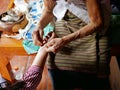 Hand of old woman waving a white string Sai Sin around her granddaughter hands - Thai traditional blessing from an elder one