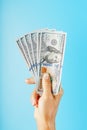 A hand with one hundred-dollar bills on a blue background Royalty Free Stock Photo