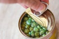 Hand open canned food in metal can on wooden background - Close up  peas canned goods non perishable food storage goods in kitchen Royalty Free Stock Photo