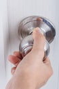 Hand opening door knob on white door Royalty Free Stock Photo