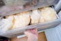 A hand opening a drawer of a freezer with frozen foods, vegetables, long-term food storage and inventory at home