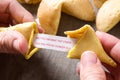 Hand opening fortune cookie with message on paper on wood Royalty Free Stock Photo