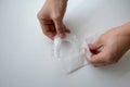 Hand opening a white package of disposable shower cap against white background Royalty Free Stock Photo