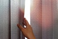 Hand opens black vertical blinds of fabric on the window. Close up Royalty Free Stock Photo