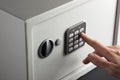 The hand opens a combination lock on the safe, a light safe on a dark background. Royalty Free Stock Photo